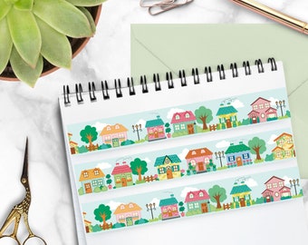 May include: A sheet of colorful washi tape with a repeating pattern of houses, trees, and flowers. The tape is on a white background with a spiral notebook.