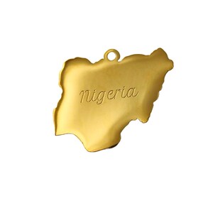 May include: A gold-colored metal charm shaped like the outline of Nigeria. The word "Nigeria" is engraved on the charm.
