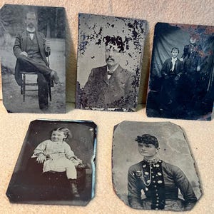 May include: Five rectangular tintype photographs featuring black and white portraits of individuals. The images show a seated man, a man with a mustache, a pair of people, a young child, and a person wearing a high-collared jacket with a chain.