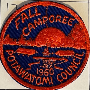 May include: Embroidered patch with a blue background and orange border. The patch reads "FALL CAMPOREE POTAWATOMI COUNCIL 1960." The design features a sunset over a body of water with trees.