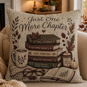 May include: A square woven throw pillow featuring the text Just One More Chapter. The design includes a stack of five books titled Fall Stories, Autumn Nights, Cozy Chapters, Sweater Weather, and Good Books Warm Hearts, a mug, glasses, and a candle.