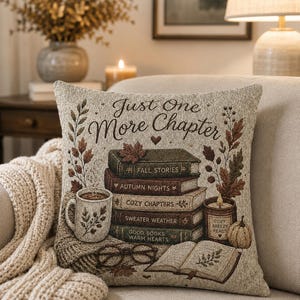 May include: A square throw pillow featuring a woven design with the text Just One More Chapter. The image displays a stack of five books titled Fall Stories, Autumn Nights, Cozy Chapters, Sweater Weather, and Good Books Warm Hearts, a mug, a candle, glasses, and an open book.