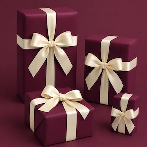 Könnte beinhalten: Vier weinrote Geschenkboxen in verschiedenen Größen, jede mit elfenbeinfarbenem Satinband und passender Schleife verpackt. Die Boxen sind vor einem weinroten Hintergrund angeordnet und bilden eine kohärente und elegante Präsentation.
