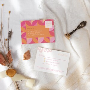May include: A pink and orange geometric patterned wedding invitation with the text "RSVP" on a white card with a wax seal and dried flowers.