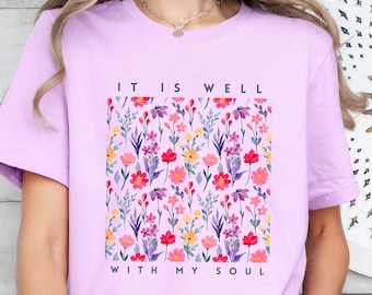 May include: Lilac t-shirt with a floral print and the text "It is well with my soul".