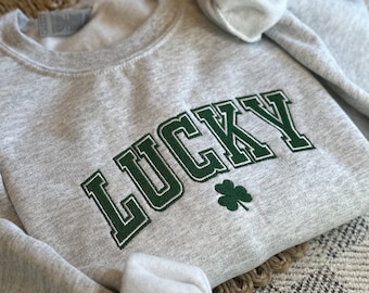 May include: A gray sweatshirt with the word "LUCKY" embroidered in green with a green four-leaf clover.
