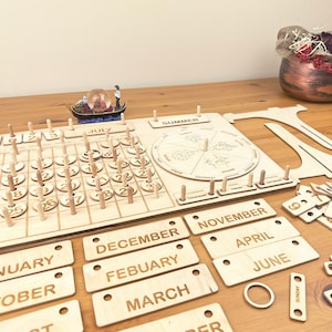 May include: Wooden perpetual calendar with a circular wooden calendar wheel, a wooden calendar grid, and wooden month labels. The calendar grid has numbers 1 through 31. The month labels include January, February, March, April, May, June, July, August, September, October, November, and December. The calendar wheel has the words "SUMMER" and "WINTER" on it.