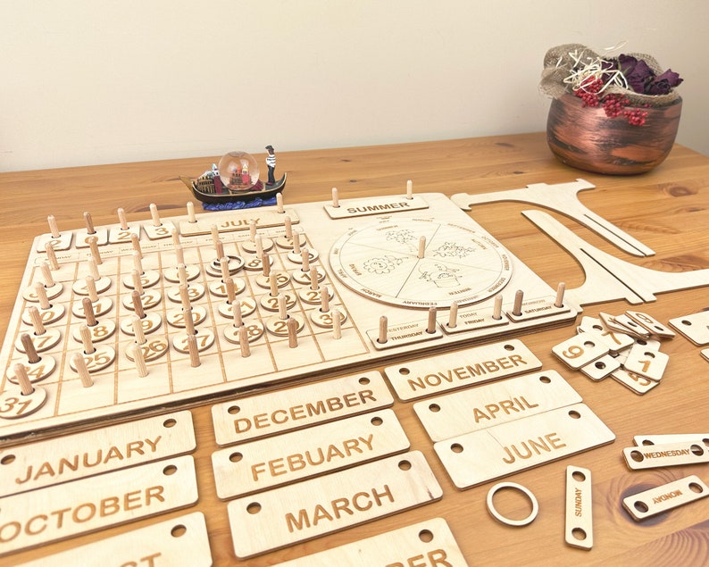 May include: Wooden perpetual calendar with a circular wooden calendar wheel, a wooden calendar grid, and wooden month labels. The calendar grid has numbers 1 through 31. The month labels include January, February, March, April, May, June, July, August, September, October, November, and December. The calendar wheel has the words "SUMMER" and "WINTER" on it.