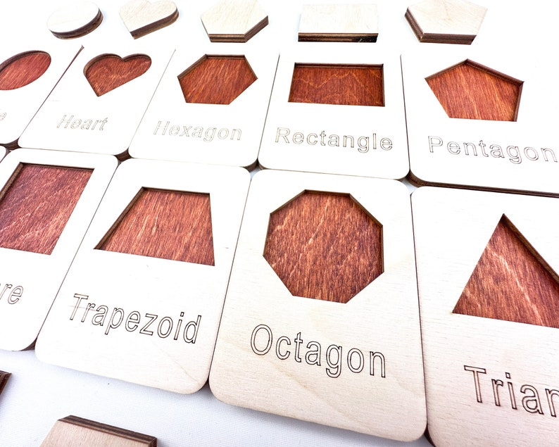 May include: Wooden learning toy with different shapes, including a heart, hexagon, rectangle, pentagon, trapezoid, octagon, and triangle. Each shape has a corresponding label.