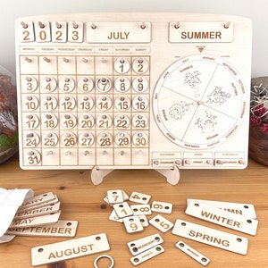 May include: Wooden calendar with a monthly calendar, a seasonal wheel, and separate pieces for days, months, and seasons. The calendar is set to July 2023. The seasonal wheel shows the seasons of the year with illustrations of flowers, leaves, and snow.