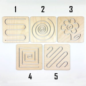May include: Five wooden tracing boards with different patterns, numbered 1 through 5. The patterns include a wavy line, a spiral, a flower, a square with concentric squares, and diagonal lines.