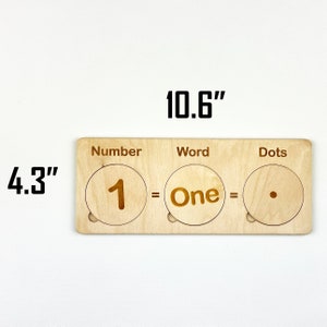 May include: Wooden learning tool with three sections labeled "Number", "Word", and "Dots". The first section shows the number "1", the second section shows the word "One", and the third section shows a single dot. The tool measures 10.6 inches long and 4.3 inches wide.