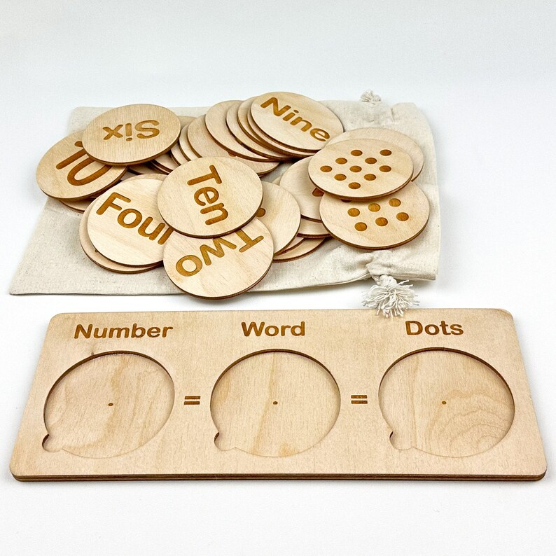 May include: Wooden learning toy with number, word, and dot matching game. The set includes a wooden tray with three sections labeled "Number", "Word", and "Dots". There are also a set of wooden circles with numbers, words, and dots on them.