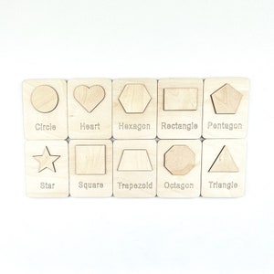 May include: Wooden cards with different shapes, including a circle, heart, hexagon, rectangle, pentagon, star, square, trapezoid, octagon, and triangle. Each card has the name of the shape written below it.