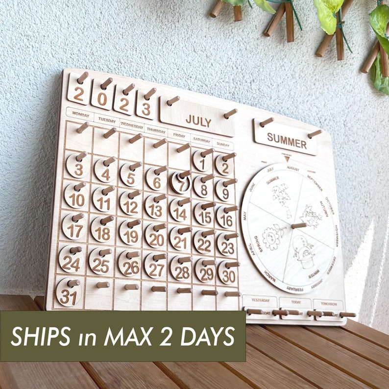 May include: Wooden calendar with a monthly calendar for July 2023 and a seasonal wheel with the months of the year. The calendar has a summer theme and the text "SHIPS in MAX 2 DAYS" is printed at the bottom.