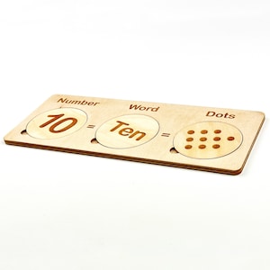 May include: Wooden learning tool with three sections labeled "Number", "Word", and "Dots". The number section shows the number "10", the word section shows the word "Ten", and the dots section shows ten dots.
