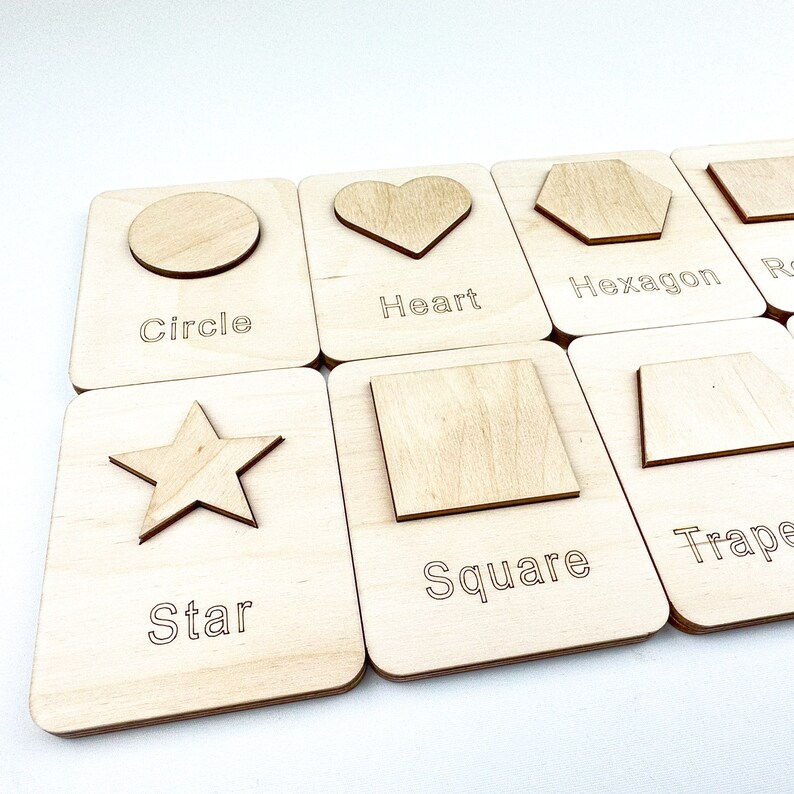 May include: Wooden learning cards with cutouts of different shapes, including a circle, heart, hexagon, square, star, and trapezoid. Each card has the name of the shape printed below the cutout.