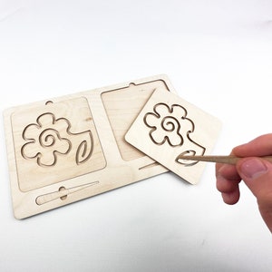 May include: Wooden tracing board with a flower design. The board has a removable piece with the same design, allowing children to trace the lines with a stylus.