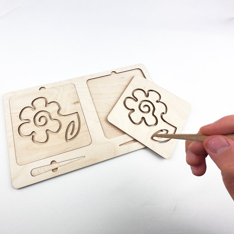May include: Wooden tracing board with a flower design. The board has a removable piece with the same design, allowing children to trace the lines with a stylus.