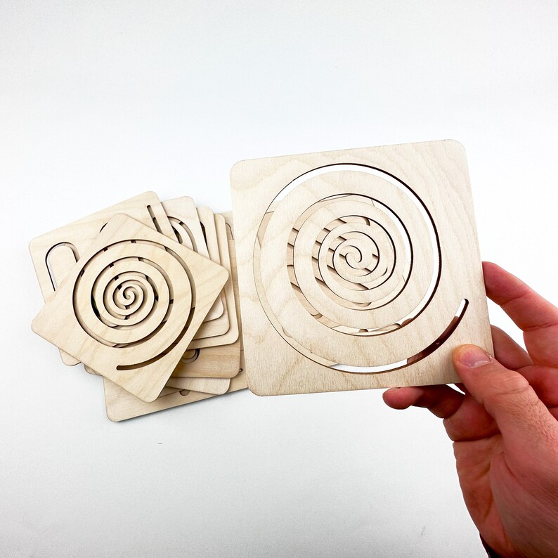 May include: A set of wooden spiral templates for crafting. The templates are made of light brown wood and have a spiral design cut out of them. The templates are stacked on top of each other, with the largest template on the bottom and the smallest template on top.