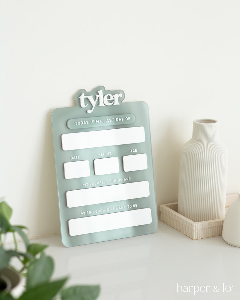 May include: A light blue acrylic growth chart with the name "tyler" at the top. The chart has spaces to fill in the date, height, age, favorite things, and what the person wants to be when they grow up.