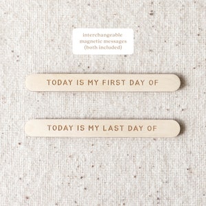 May include: Two wooden signs with the text "TODAY IS MY FIRST DAY OF" and "TODAY IS MY LAST DAY OF" on a beige fabric background. The signs are interchangeable and magnetic.