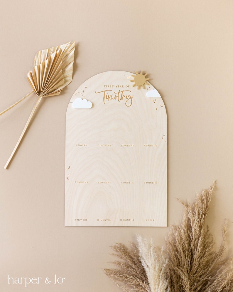 May include: A wooden growth chart with a sun and clouds design. The chart is labeled "First Year of Timothy" and has spaces for each month of the year.