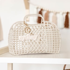 May include: A white plastic tote bag with a gold chain and a white plastic keychain that says "sydney".
