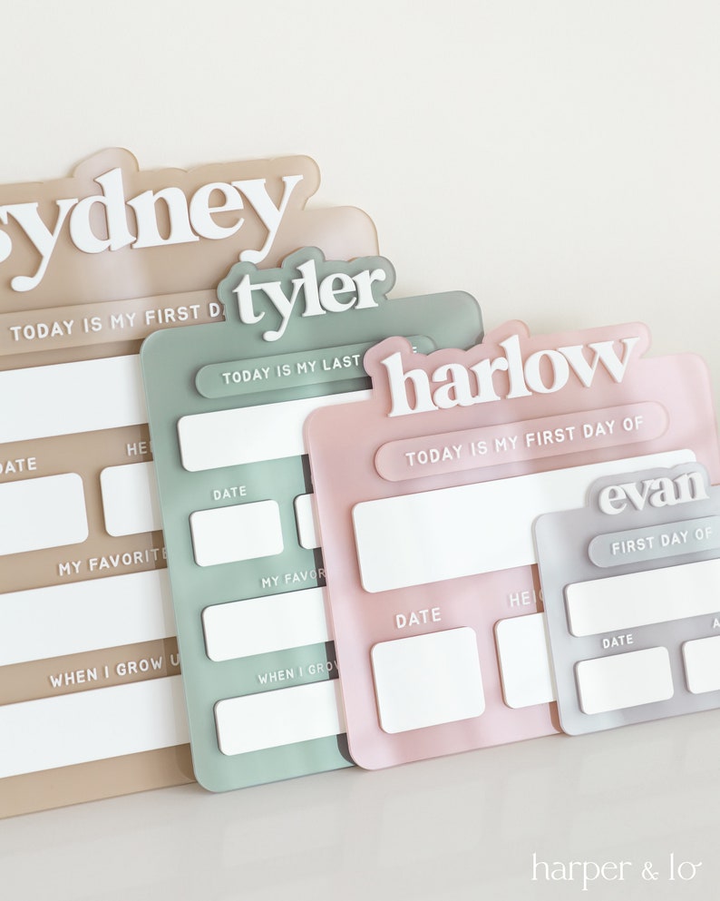 May include: Four personalized acrylic signs with blank spaces for writing in. The signs are in different colors: beige, green, pink, and gray. The signs have the names Sydney, Tyler, Harlow, and Evan. The signs have the text "Today is my first day of" and "Today is my last day of".