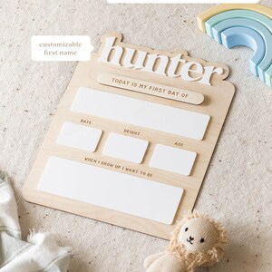 May include: A wooden growth chart with a white text box for a customizable first name. The chart has the text "hunter" and "TODAY IS MY FIRST DAY OF". There are white text boxes for date, height, age, and "WHEN I GROW UP I WANT TO BE".