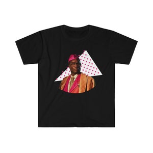 Puede incluir: Una camiseta negra con un gráfico de un hombre con un sombrero rosa y una chaqueta marrón. El gráfico está sobre un triángulo blanco con lunares rosas.