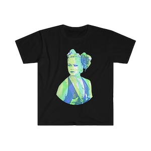 Könnte beinhalten: Ein schwarzes T-Shirt mit einer bunten Grafik einer Frau mit einer Blume im Haar. Die Frau trägt ein blaues und grünes Kleid.