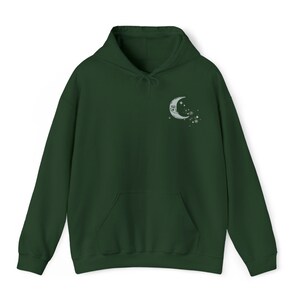 May include: A dark green hooded sweatshirt with a crescent moon and stars design on the left chest.