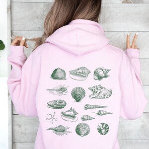 May include: A pink hoodie with a green print of various seashells on the back.