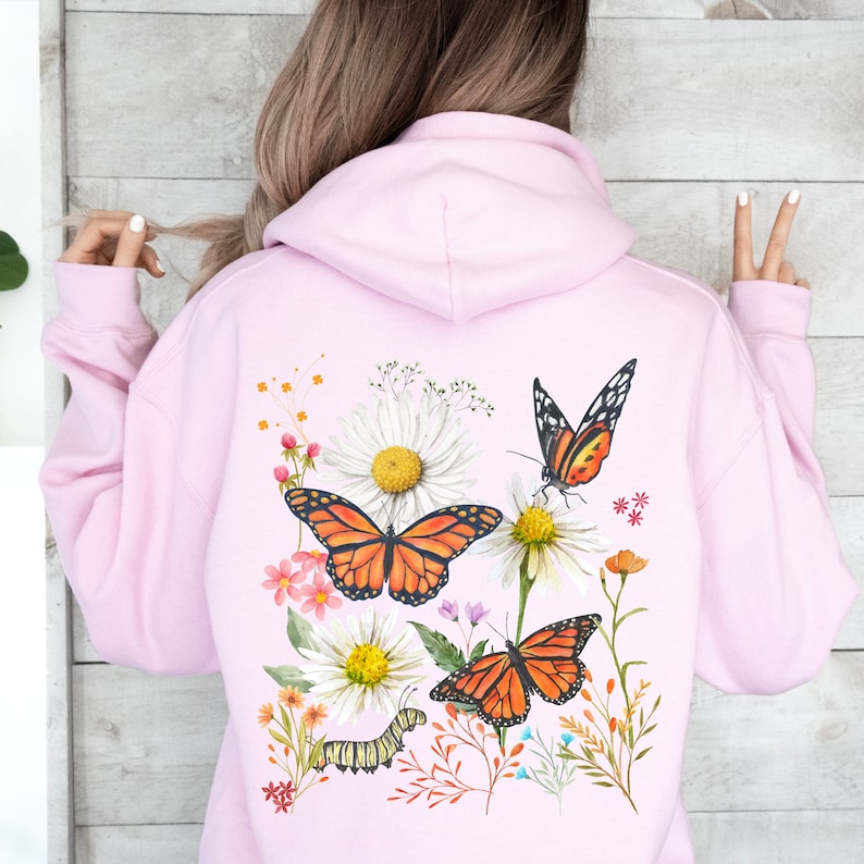 Pu&ograve; includere: Felpa rosa con un design floreale con farfalle, margherite e verde. Il design &egrave; sul retro della felpa.