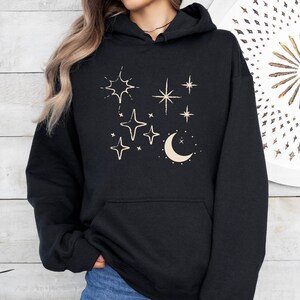 May include: Black hooded sweatshirt with a cream coloured design of a crescent moon and stars.