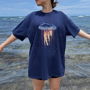 May include: A navy blue t-shirt with a graphic of a jellyfish with orange tentacles on a dark blue background.