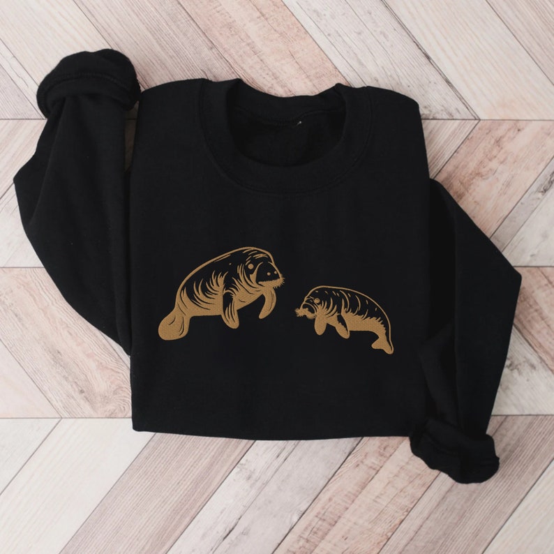May include: Black sweatshirt with a gold outline of two manatees, one larger than the other.