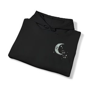 May include: Black hooded sweatshirt with a crescent moon and stars graphic on the front.