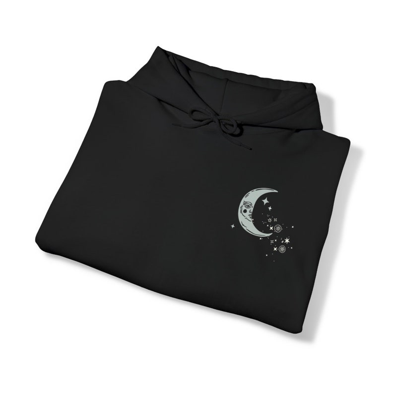 May include: Black hooded sweatshirt with a crescent moon and stars graphic on the front.