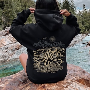 May include: Black hoodie with a gold octopus graphic on the back. The octopus is surrounded by waves and a sun.