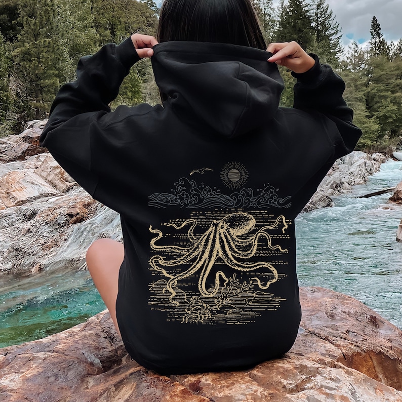 May include: Black hoodie with a gold octopus graphic on the back. The octopus is surrounded by waves and a sun.