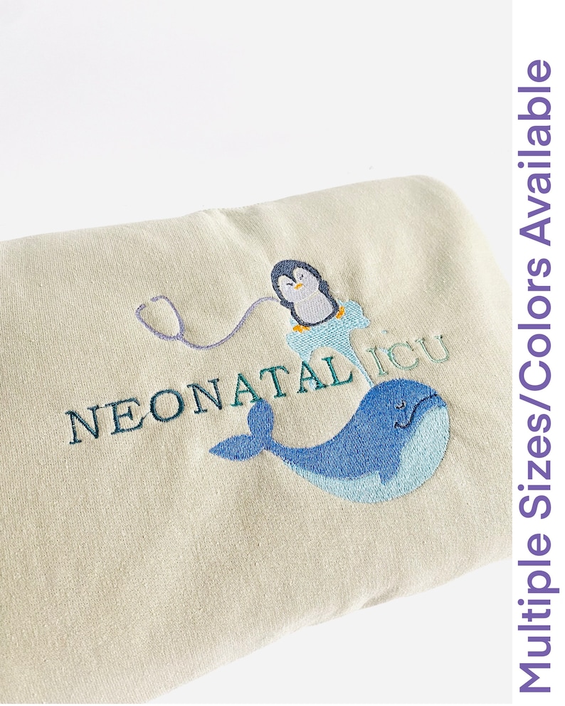 Pode incluir: Um item bordado bege com um pinguim, um estetosc&oacute;pio e uma baleia azul, com o texto "NEONATAL ICU." A imagem tamb&eacute;m inclui o texto "Multiple Sizes/Colors Available."