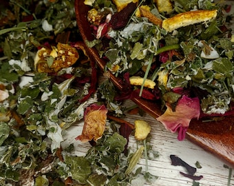 May include: A wooden spoon filled with a blend of dried herbs, flowers, and fruit peels. The ingredients include green leaves, red rose petals, orange peels, and cinnamon sticks.