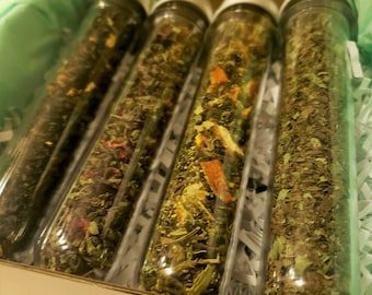 May include: Four glass tubes filled with different types of loose leaf tea. The tea blends include green tea, black tea, and herbal tea.