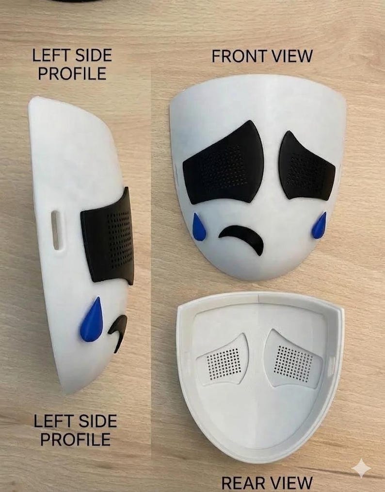 May include: A white mask with black eye and eyebrow shapes, and blue teardrops. The mask has a sad face design. The image shows the front, side, and rear views of the mask. The text "LEFT SIDE PROFILE", "FRONT VIEW", and "REAR VIEW" are visible.