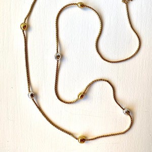 May include: A gold chain necklace with alternating gold and silver round beads. The chain is a twisted rope design.