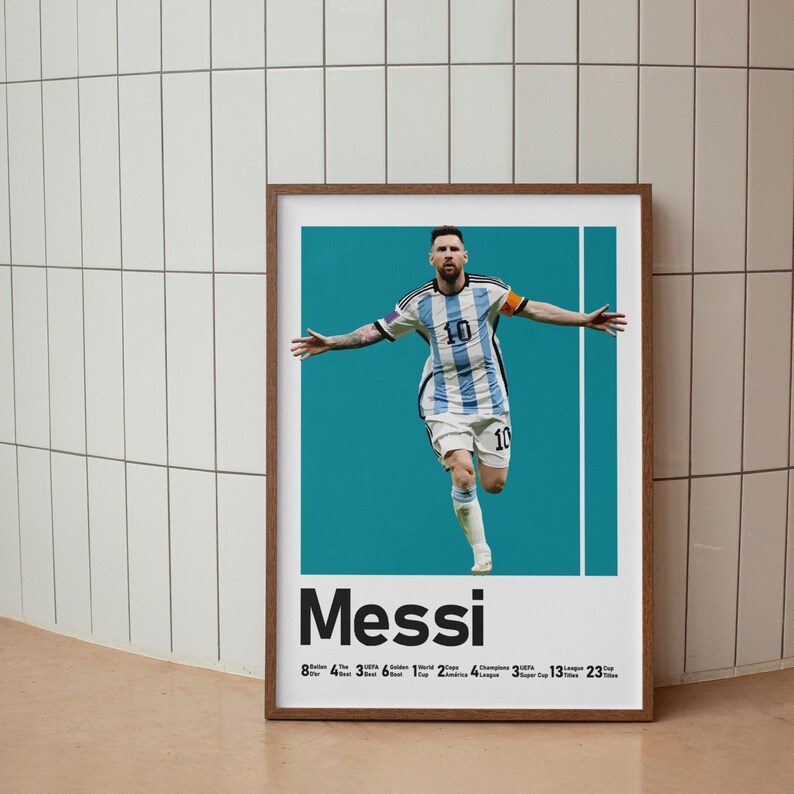May include: Framed poster featuring Lionel Messi in an Argentina soccer uniform, arms outstretched. The poster has a teal background with the name "Messi" in bold letters. Below the name are numbers and titles.