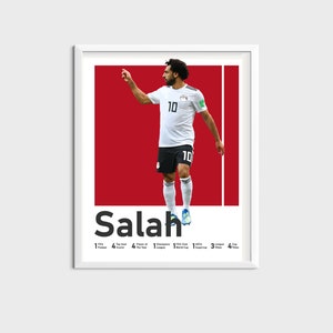 K&ouml;nnte beinhalten: Ein wei&szlig; gerahmtes Poster mit rotem Hintergrund, auf dem ein Fu&szlig;ballspieler in einem wei&szlig;en Trikot mit der Nummer 10 zu sehen ist. Der Spieler feiert ein Tor. Das Poster tr&auml;gt den Text "Salah" in schwarzen Buchstaben unten. Das Poster enth&auml;lt auch eine Liste der Leistungen des Spielers.