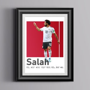K&ouml;nnte beinhalten: Ein gerahmtes Poster mit einem Foto von Mohamed Salah, einem &auml;gyptischen Profi-Fu&szlig;baller, der ein wei&szlig;es Trikot mit der Nummer 10 tr&auml;gt. Das Poster hat einen roten Hintergrund und den Text "Salah" in Wei&szlig;. Das Poster enth&auml;lt auch eine Liste von Salahs Leistungen, darunter "1x FIFA Puskas Award", "4x Premier League", "4x Spieler des Jahres", "1x Champions League", "1x FIFA Club World Cup", "3x UEFA Super Cup" und "4x Pokaltitel".